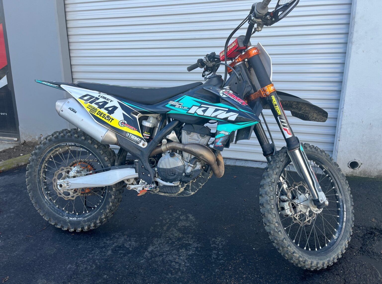 A dirt bike is parked in front of a garage door.