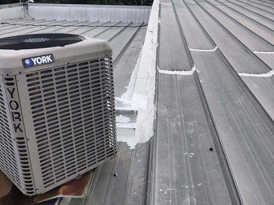 York air conditioning unit on a metal roof, with sealant applied along a seam.