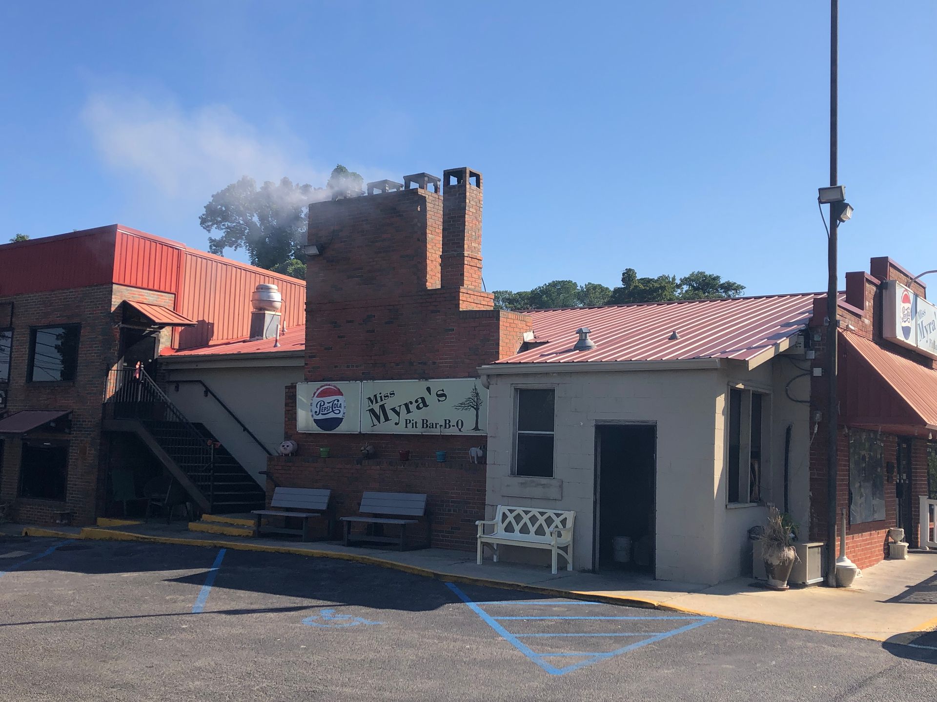Restaurant exterior with red roof, brick chimney, and sign in Japanese. Smoke rising in the background.