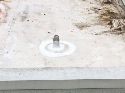 A metal pipe is centered on a light-colored surface, surrounded by circular white markings, possibly concrete.