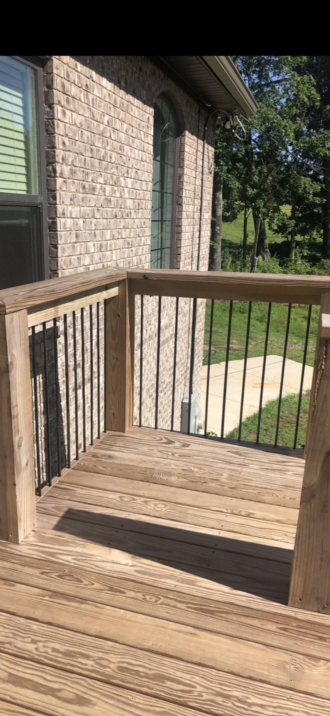 Wooden deck with railings next to a brick building.