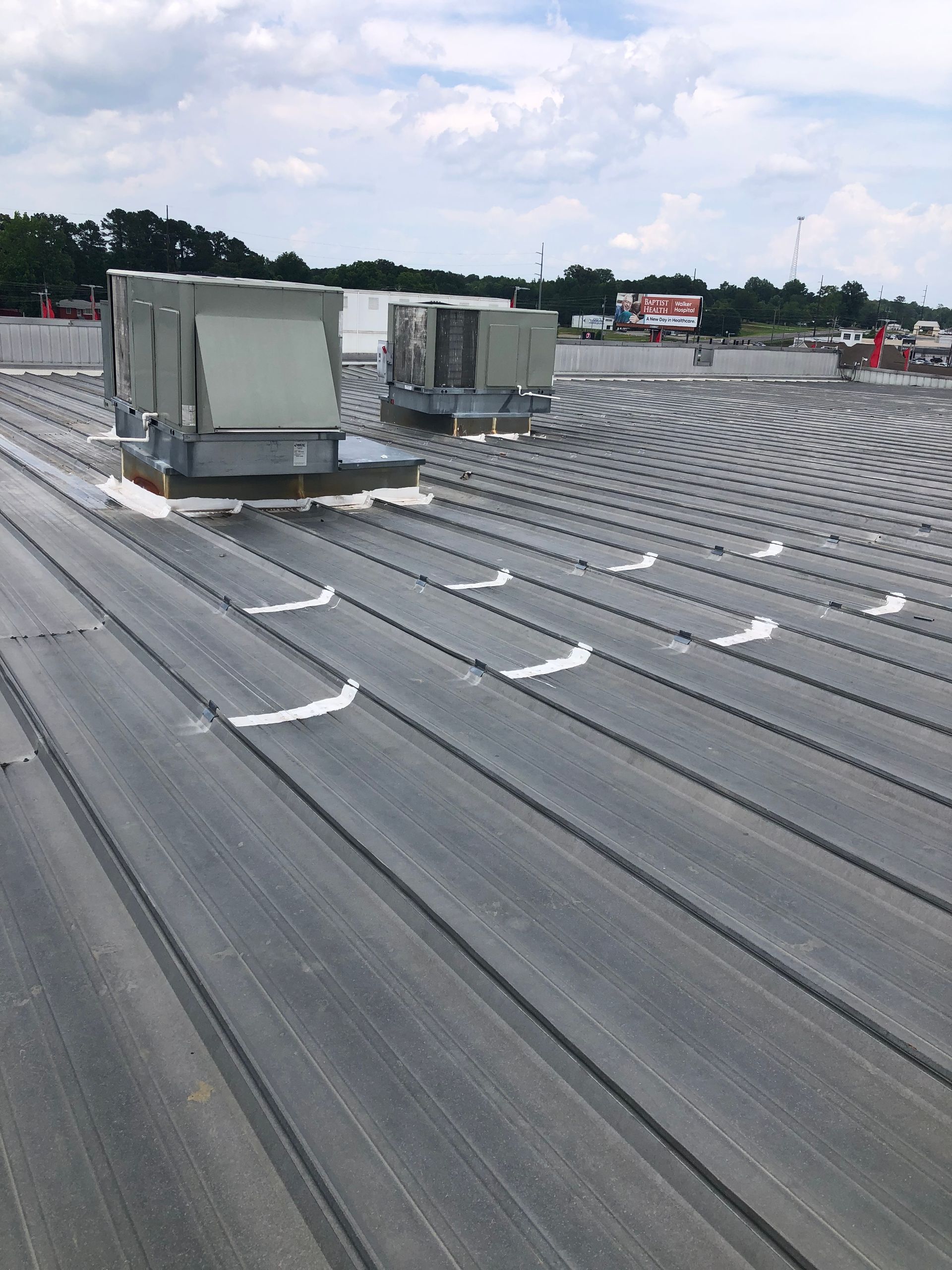 Metal roof with HVAC units. Cloudy sky in the background.