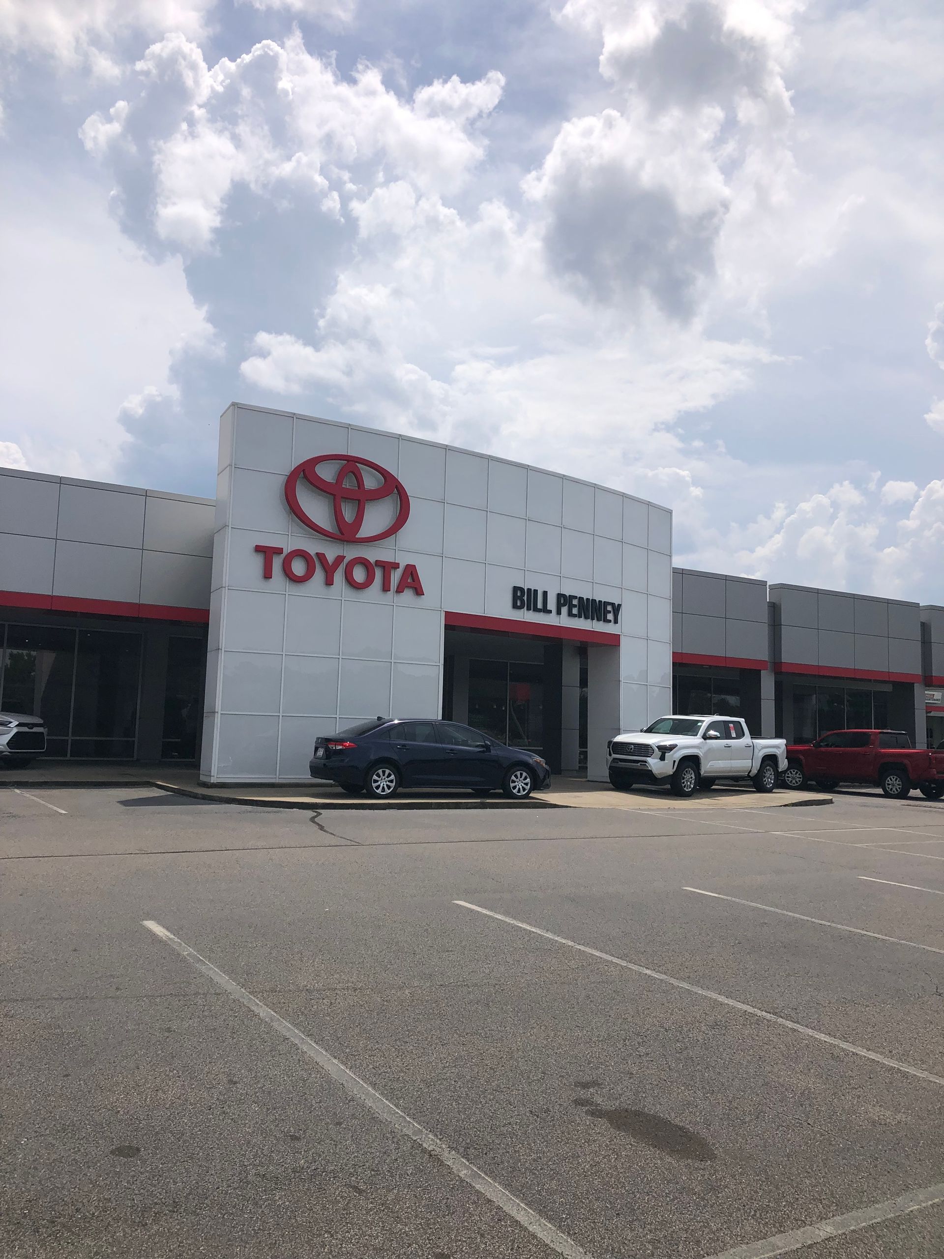 Toyota dealership with cars in front, under a cloudy sky.
