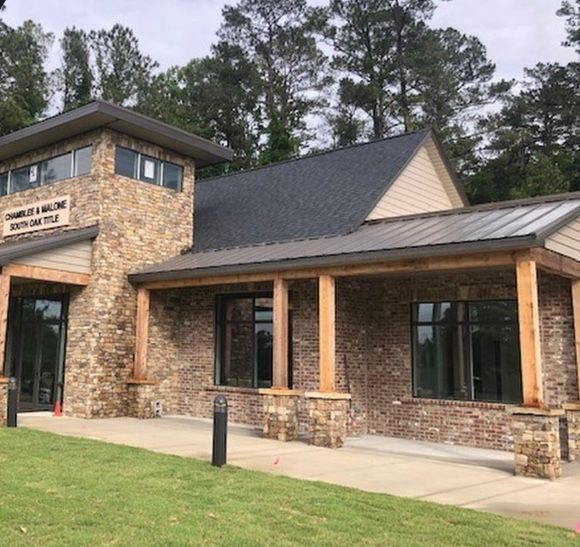 Stone and brick building with a covered entrance, ramp, and dark roof.