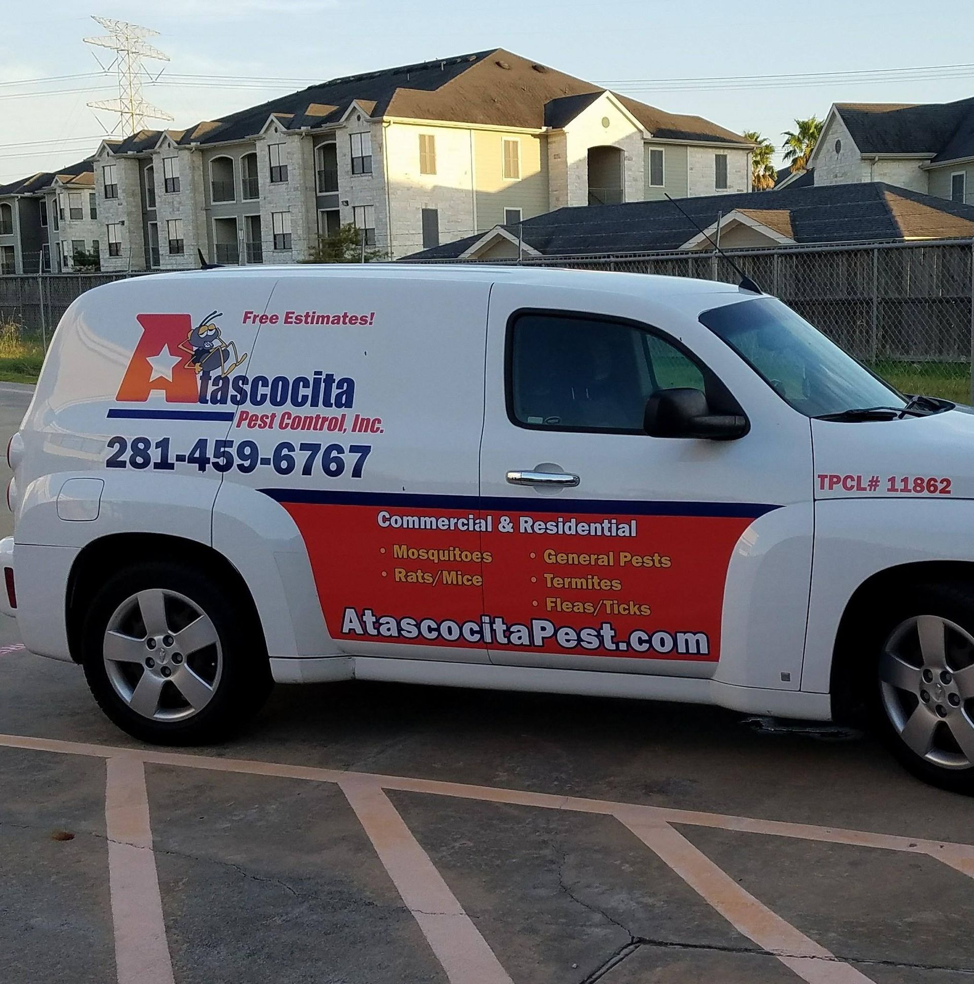 White pest control van parked in front of an apartment building; red and blue company logo and text on the side.