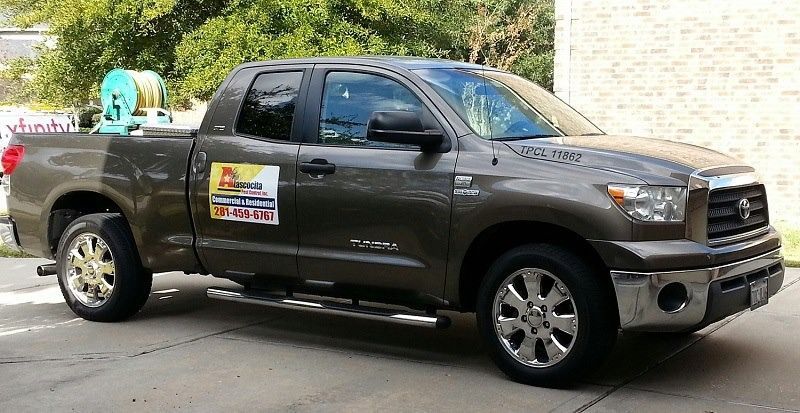 Brown Toyota Tundra pickup truck with a hose reel in the truck bed, parked on concrete.