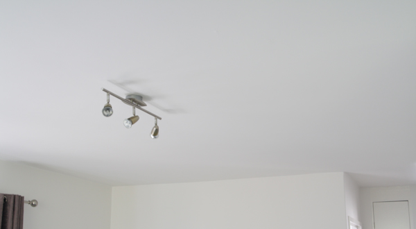 White ceiling with a silver track light fixture with three spotlights.
