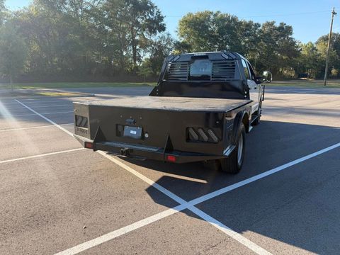 Black flatbed tow truck parked in a mostly empty lot, viewed from the rear.