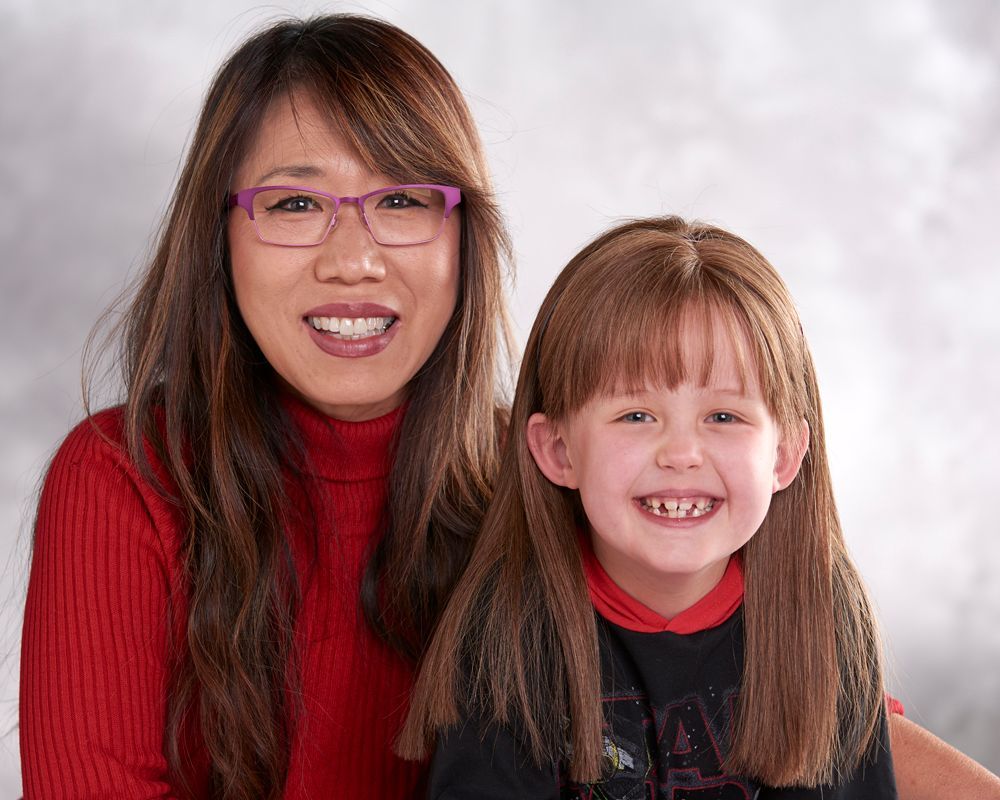 A woman and a little girl are posing for a picture and smiling for the camera.