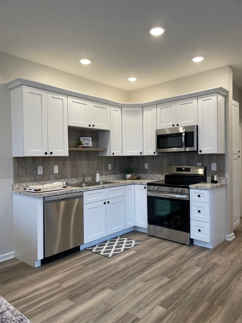 White kitchen with stainless steel appliances and gray countertops and flooring.