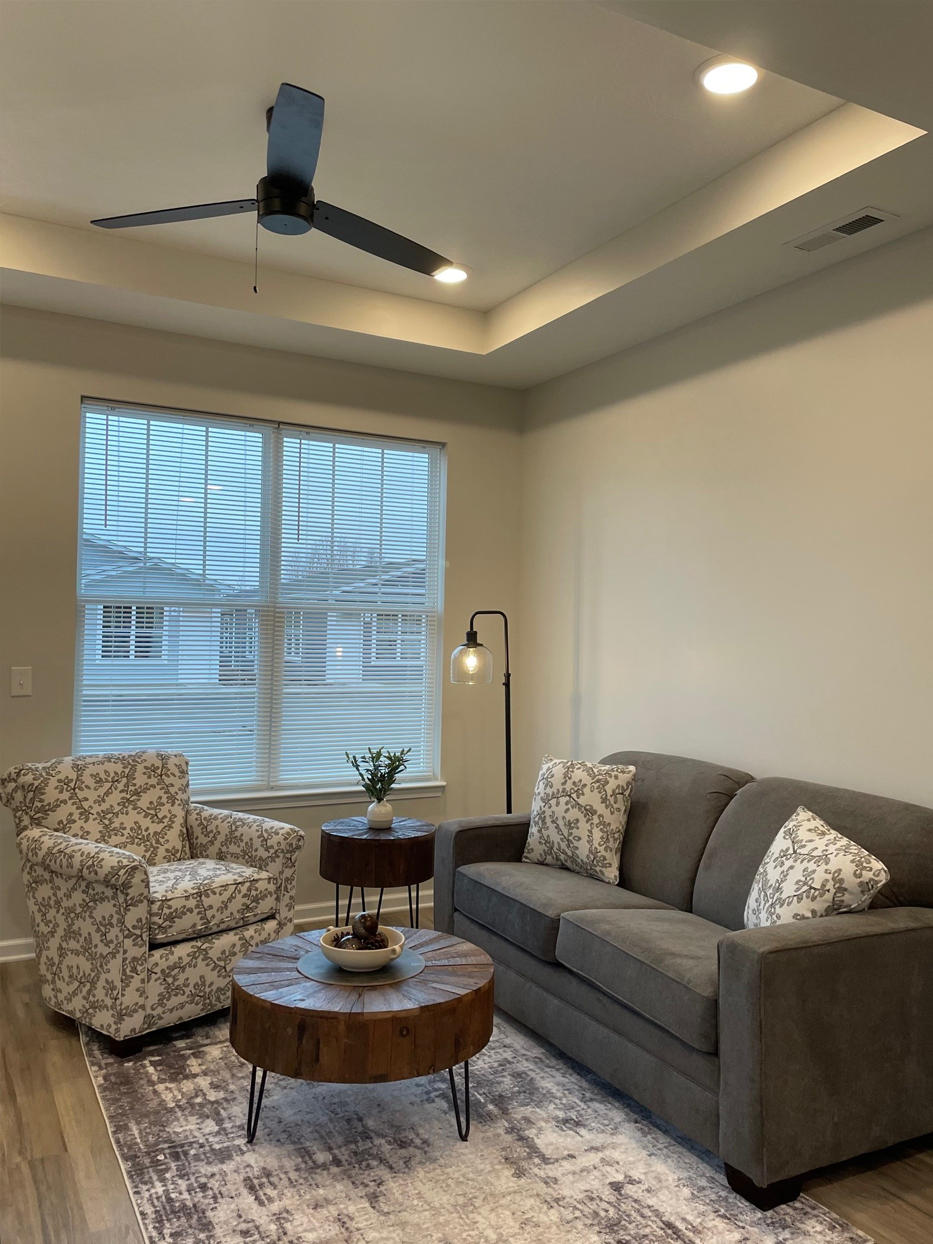 Living room with gray sofa, floral armchair, coffee table, and ceiling fan.