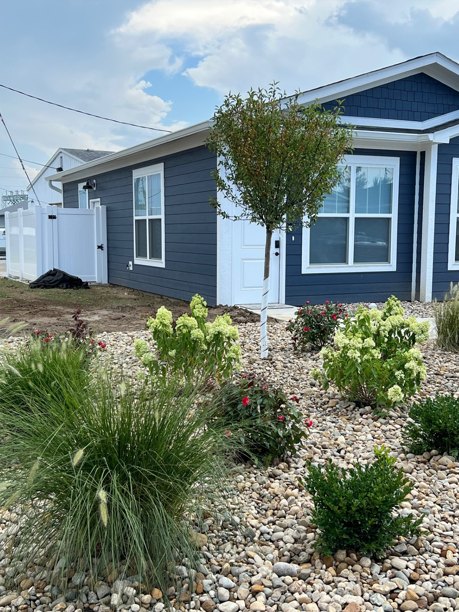 Blue house with white trim and a rock garden in front.