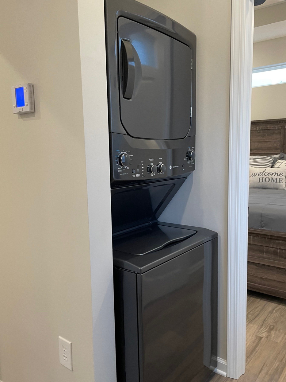 Stacked gray washer and dryer unit in a neutral-colored alcove.