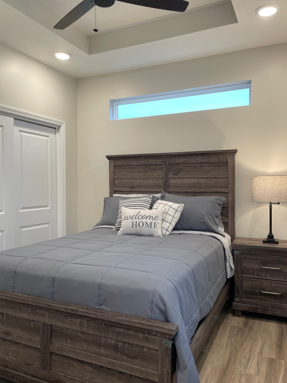 Bedroom with gray bedding, wooden furniture, and a window.