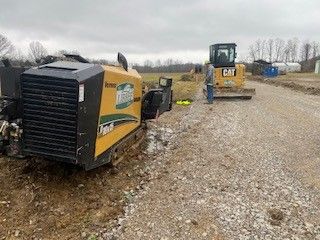 A man is standing next to a bulldozer on a gravel road.