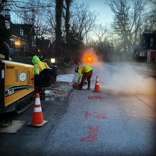 A group of construction workers are working on the side of a road.