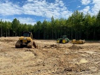 A bulldozer and a tractor are working in a muddy field.