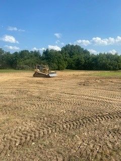 A bulldozer is sitting in the middle of a dirt field.