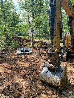 A bulldozer is digging a hole in the dirt in the woods.