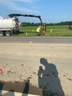 A man is standing on the side of the road next to a vacuum truck.