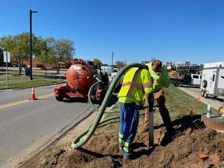 A man is using a hose to dig a hole in the ground.