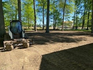 A bobcat is sitting in the middle of a dirt field.