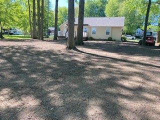 A house is surrounded by trees and dirt in a residential area.
