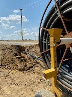 A large hose reel is sitting in the middle of a dirt field.