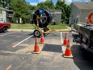 A hose reel is sitting on top of a trailer in a parking lot.