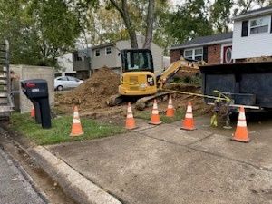 A yellow excavator is sitting on the side of the road next to a pile of dirt.