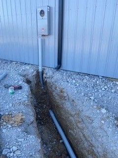 A pipe is being installed in a trench next to a building.
