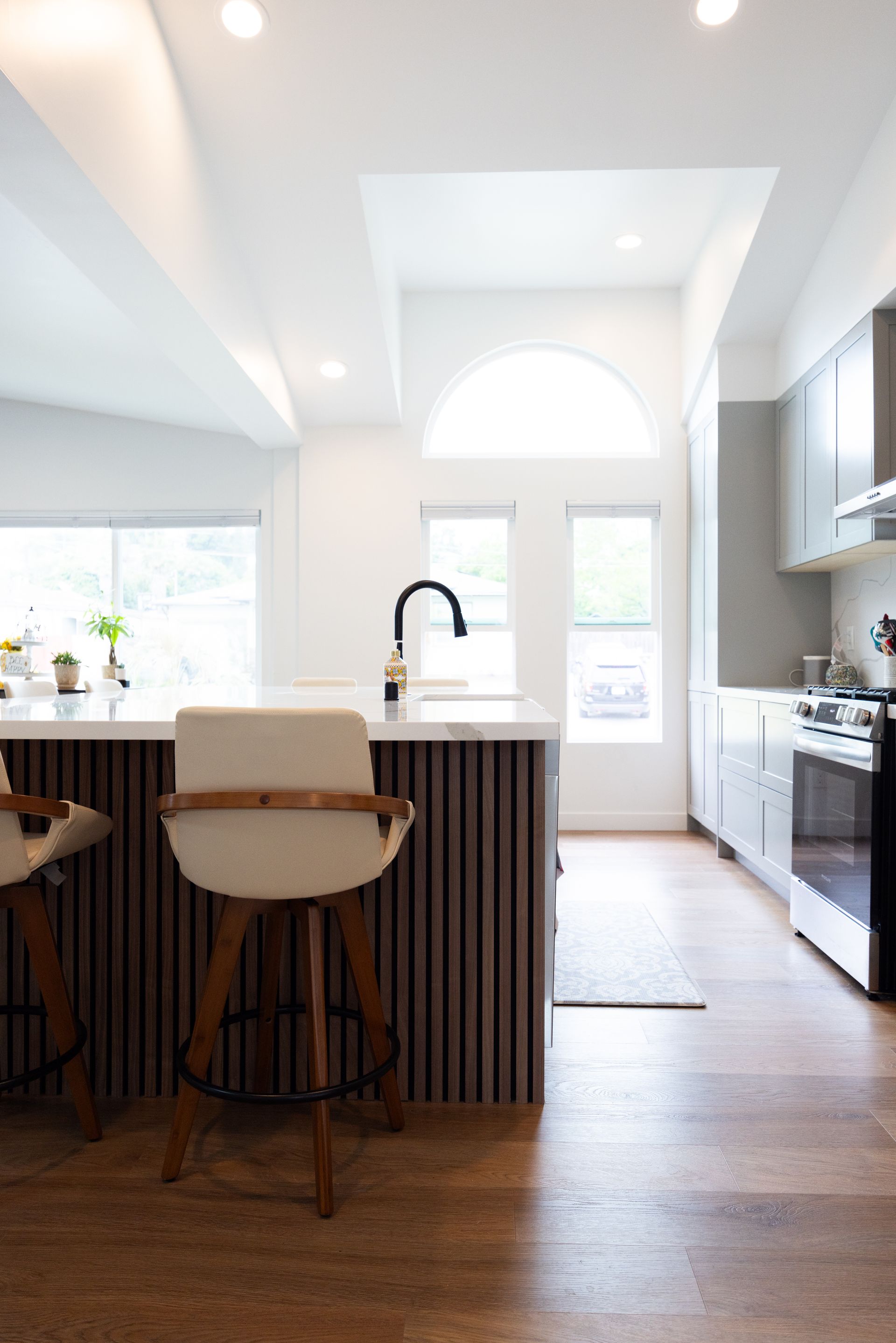 Bright modern kitchen with island, bar stools, white cabinets, and hardwood floors