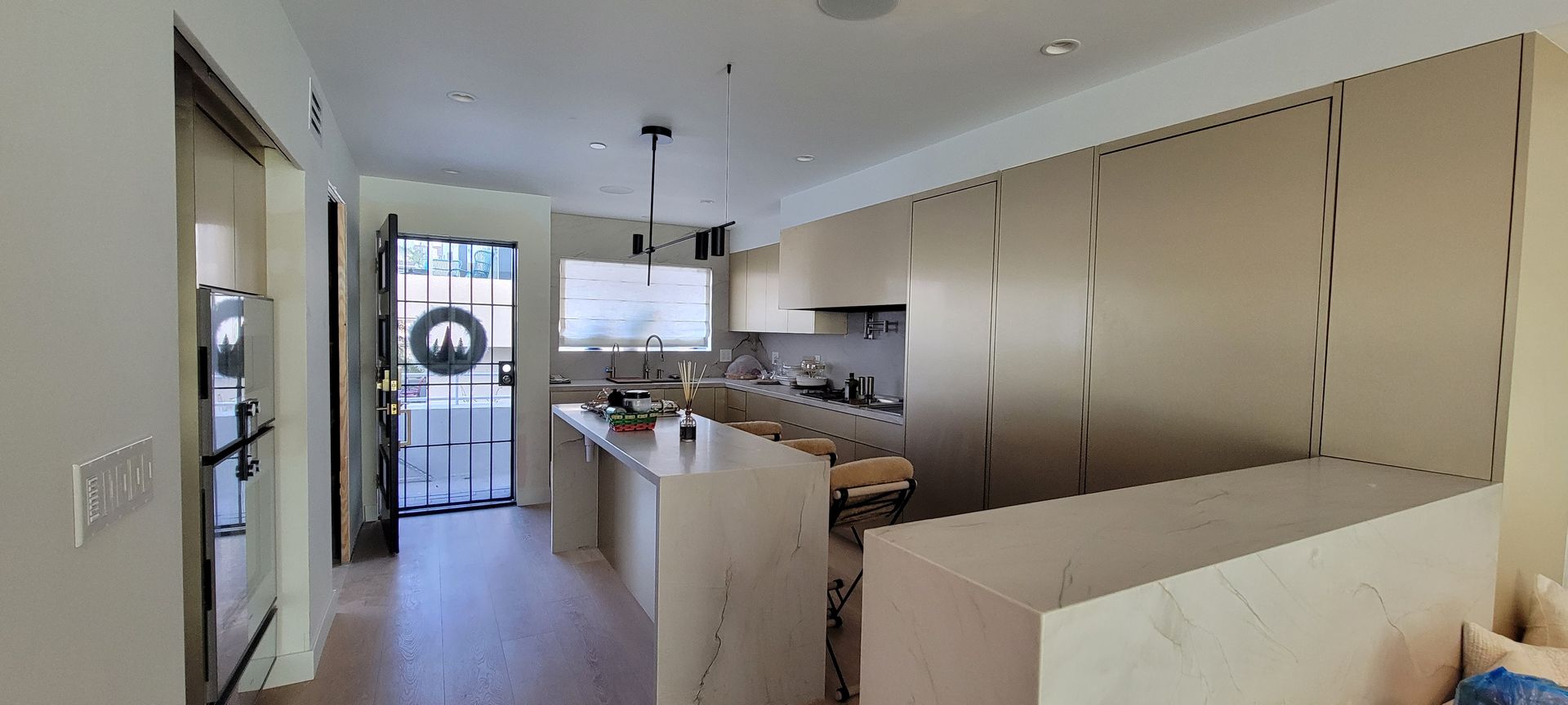 Bright modern kitchen with white cabinets, island, and glass doors leading outside