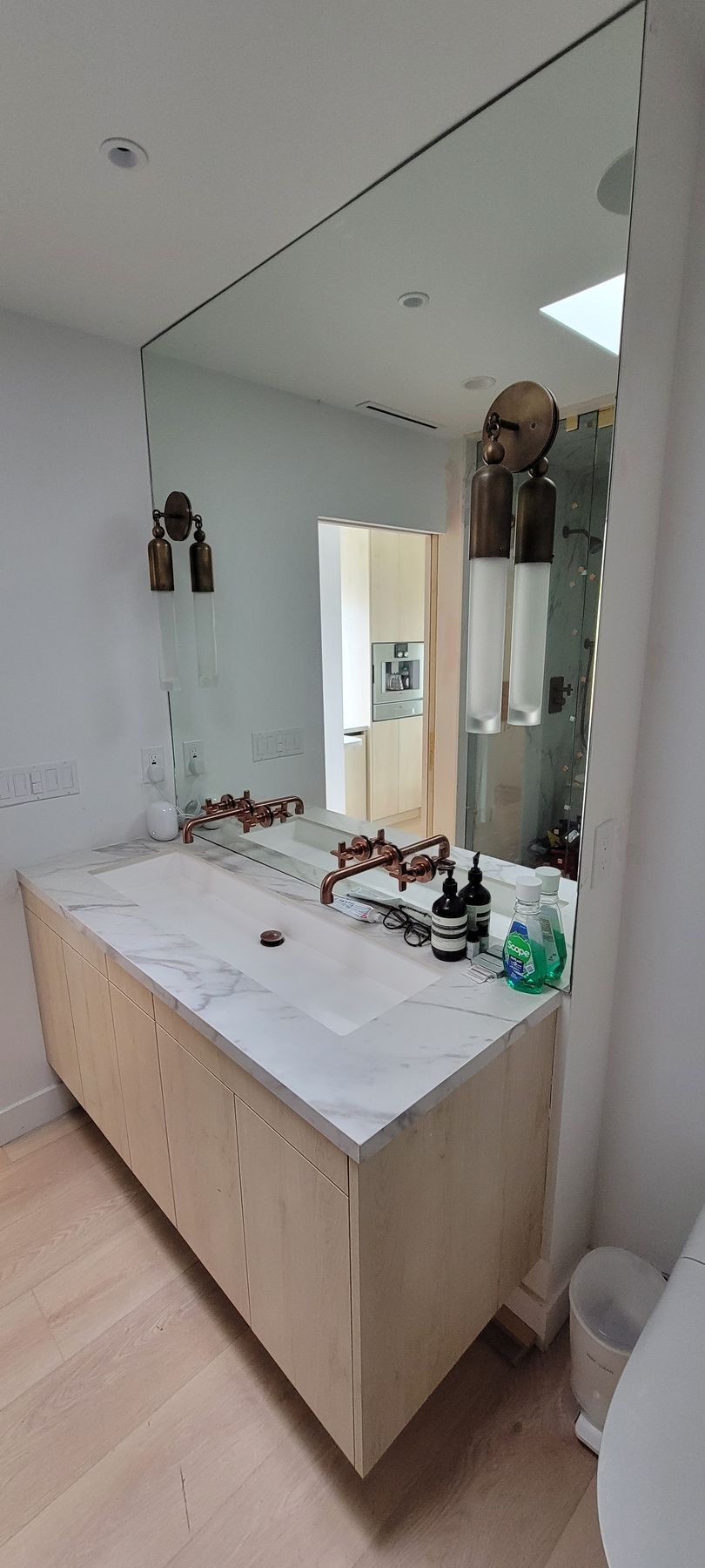 Bathroom vanity with white countertop, large mirror, and assorted toiletries on top