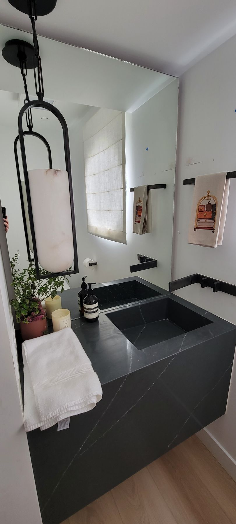 Modern bathroom with black vanity, rectangular sink, mirror cabinet, and pendant lights