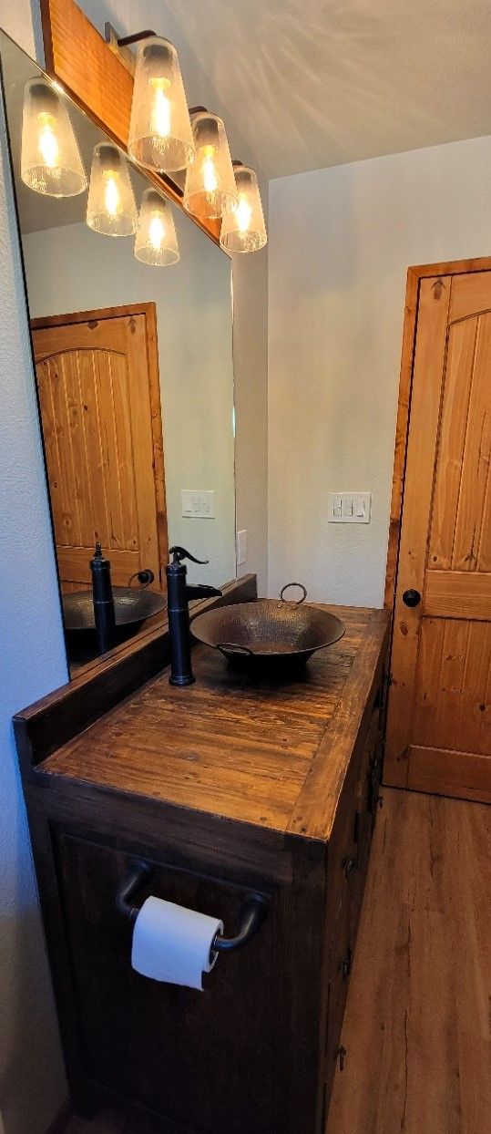 Modern bathroom vanity with vessel sink, black faucet, wood cabinets, and pendant lights