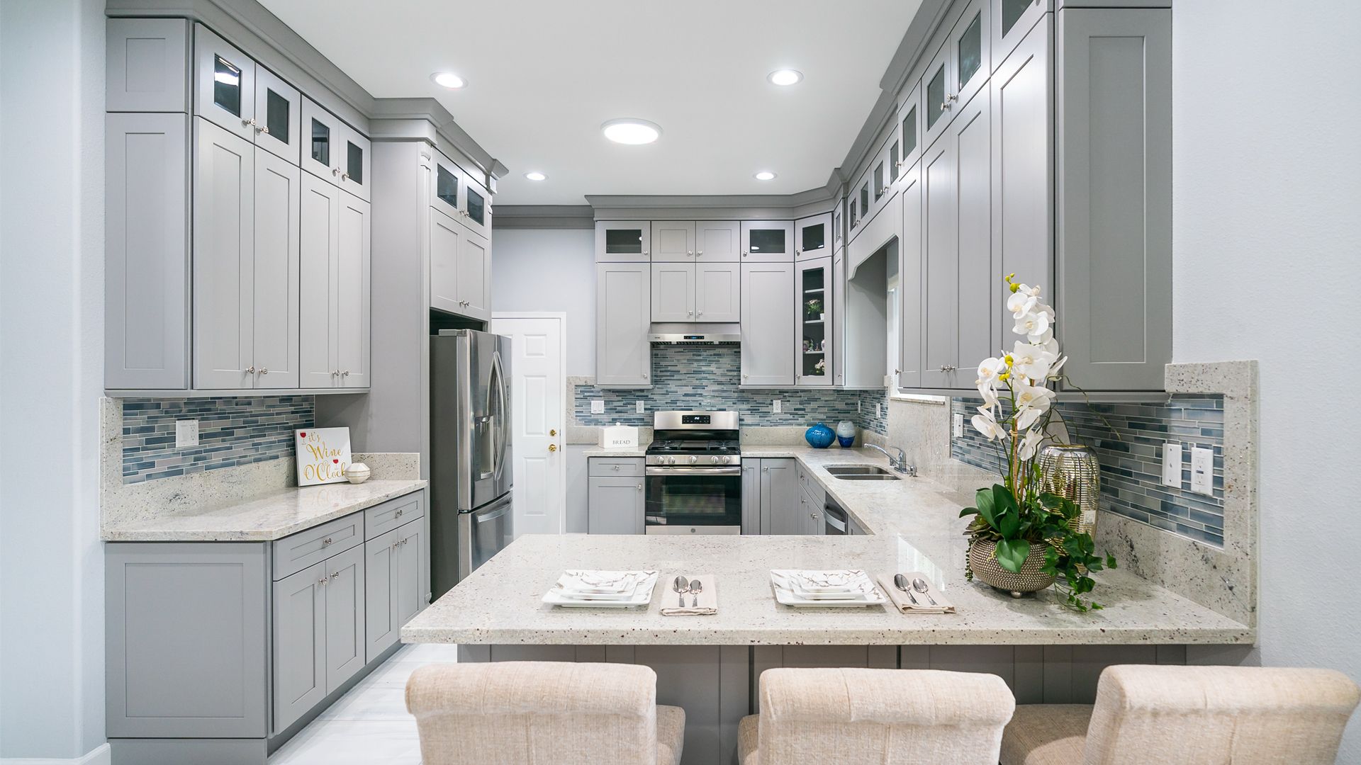 Bright modern kitchen with white cabinets, gray countertops, and a large island with seating