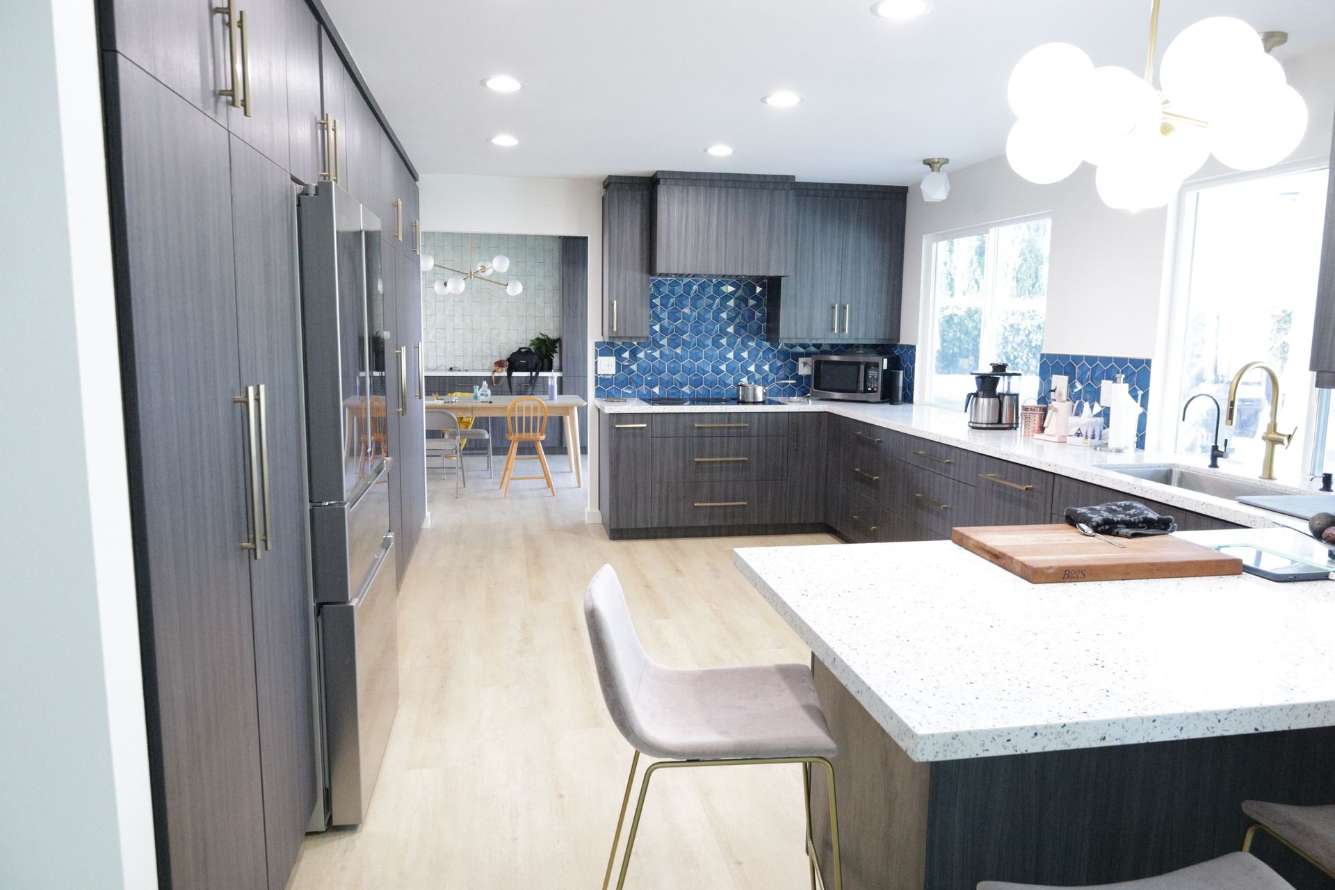 Modern kitchen with gray cabinets, white island, barstool, and bright recessed lighting
