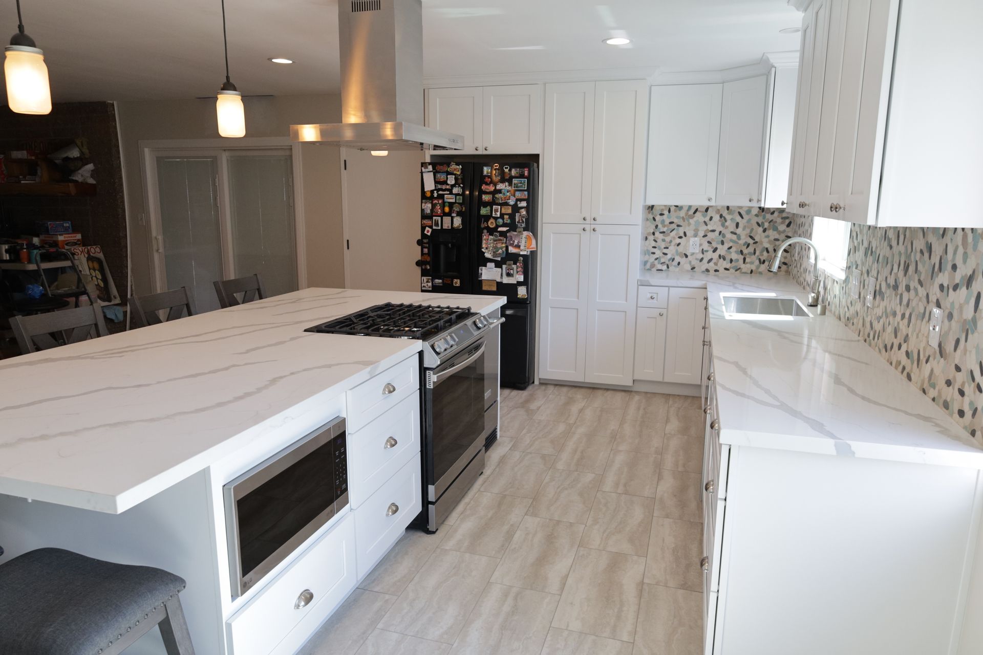 Bright modern kitchen with white cabinets, island, tile backsplash, and light wood floors