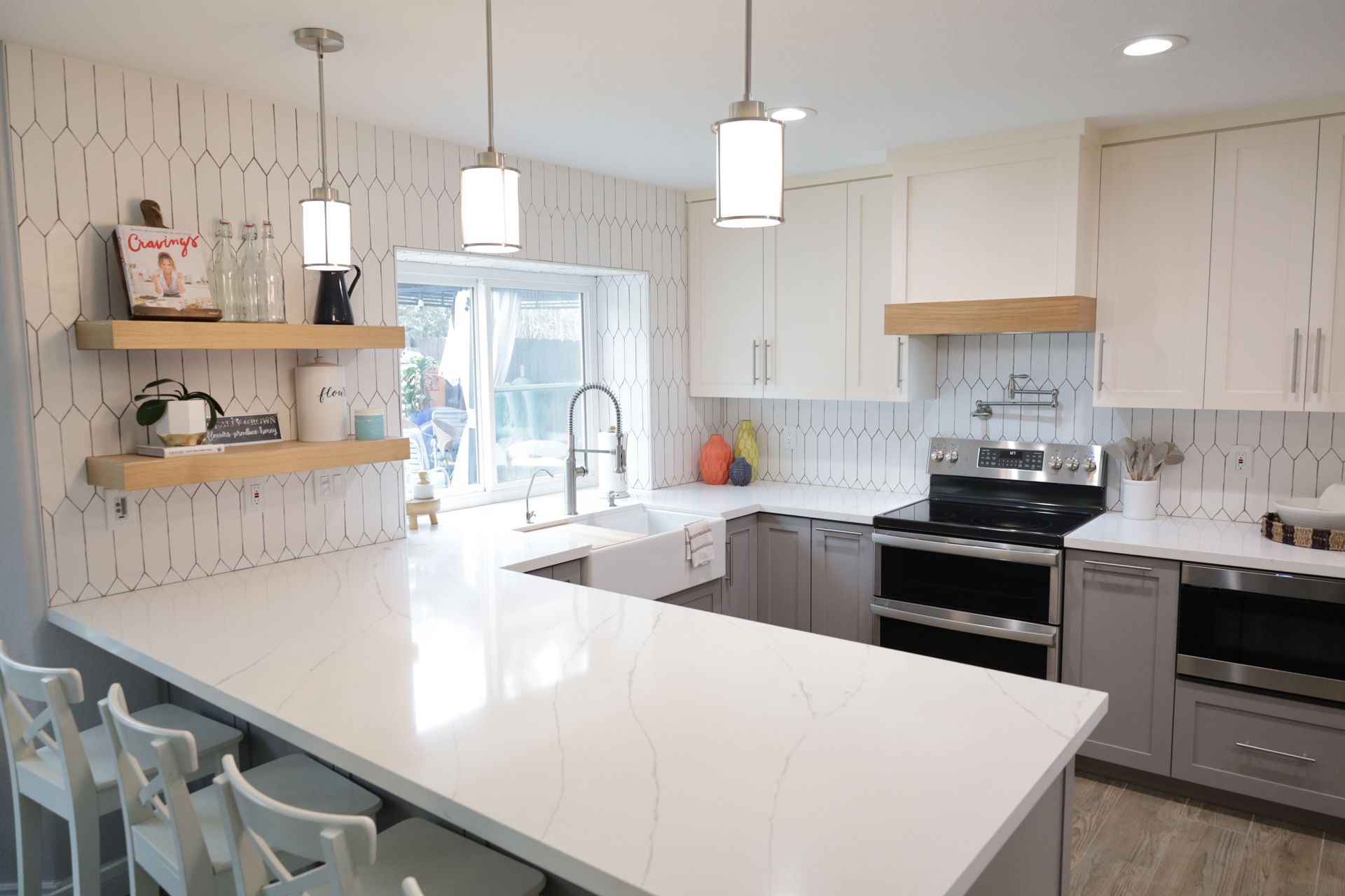 Bright modern kitchen with white cabinets, island, pendant lights, and stainless steel appliances