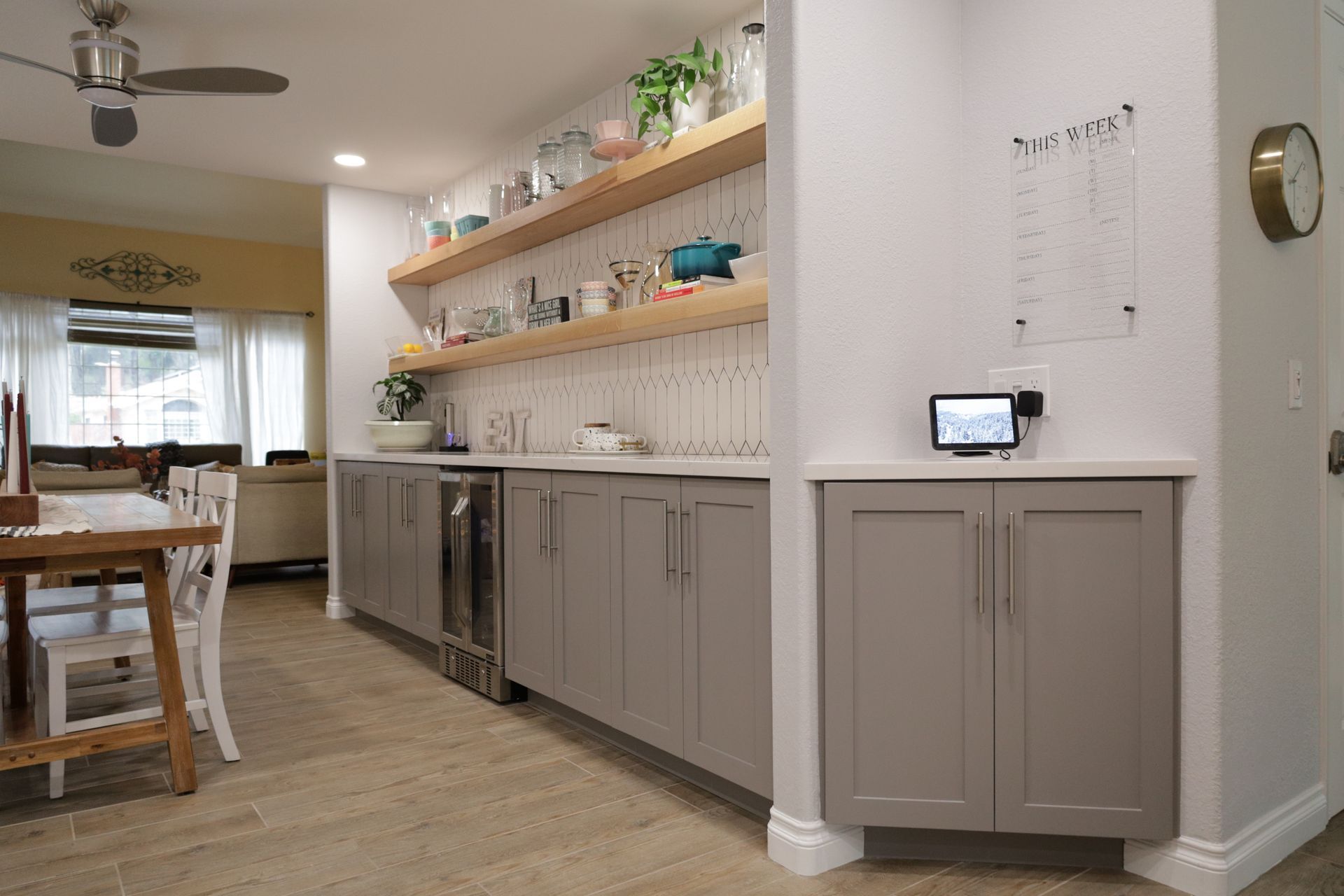 Modern kitchen with gray cabinets, open shelves, and a breakfast nook leading to a dining area
