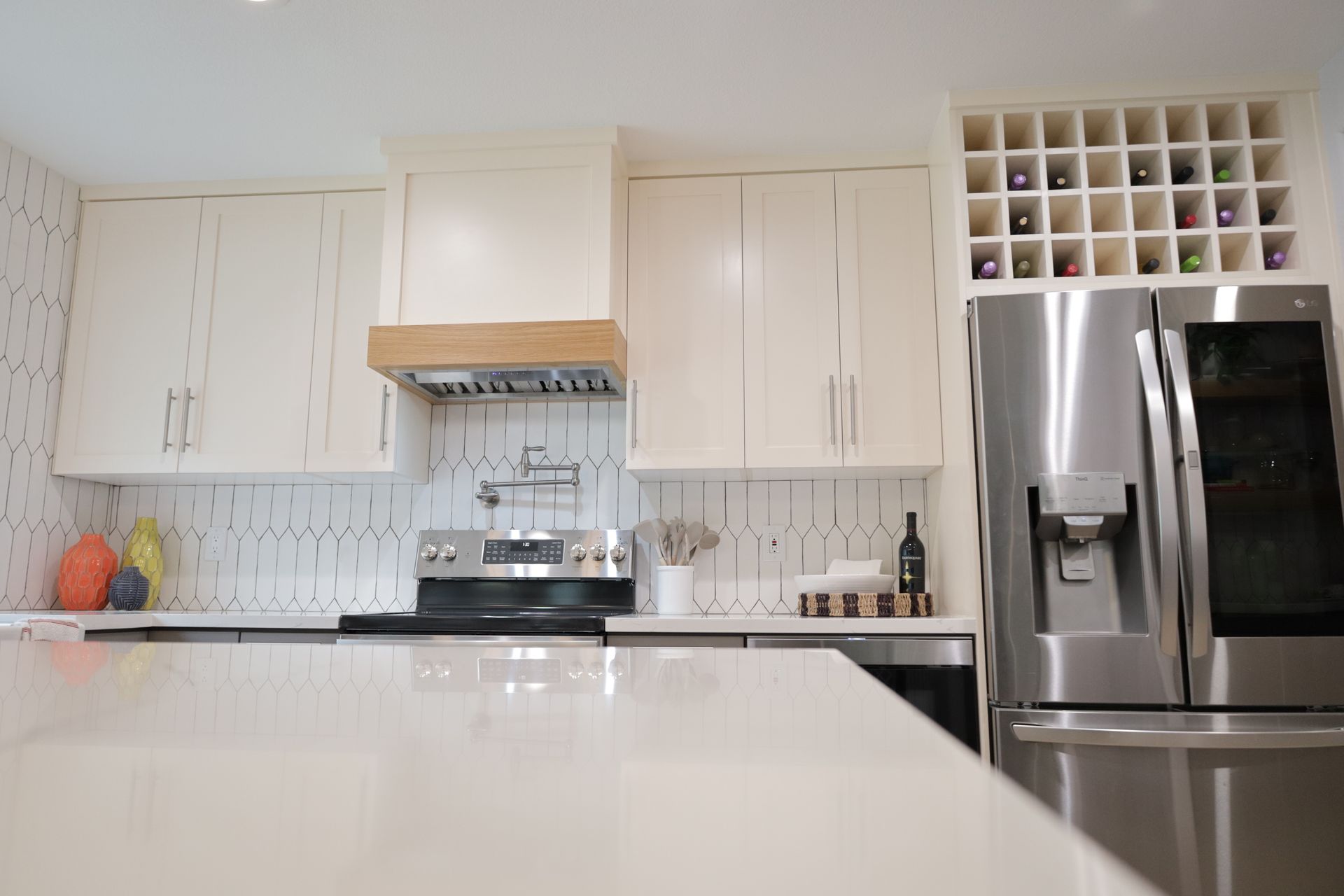 Bright modern kitchen with white cabinets, stainless steel fridge, and a black countertop