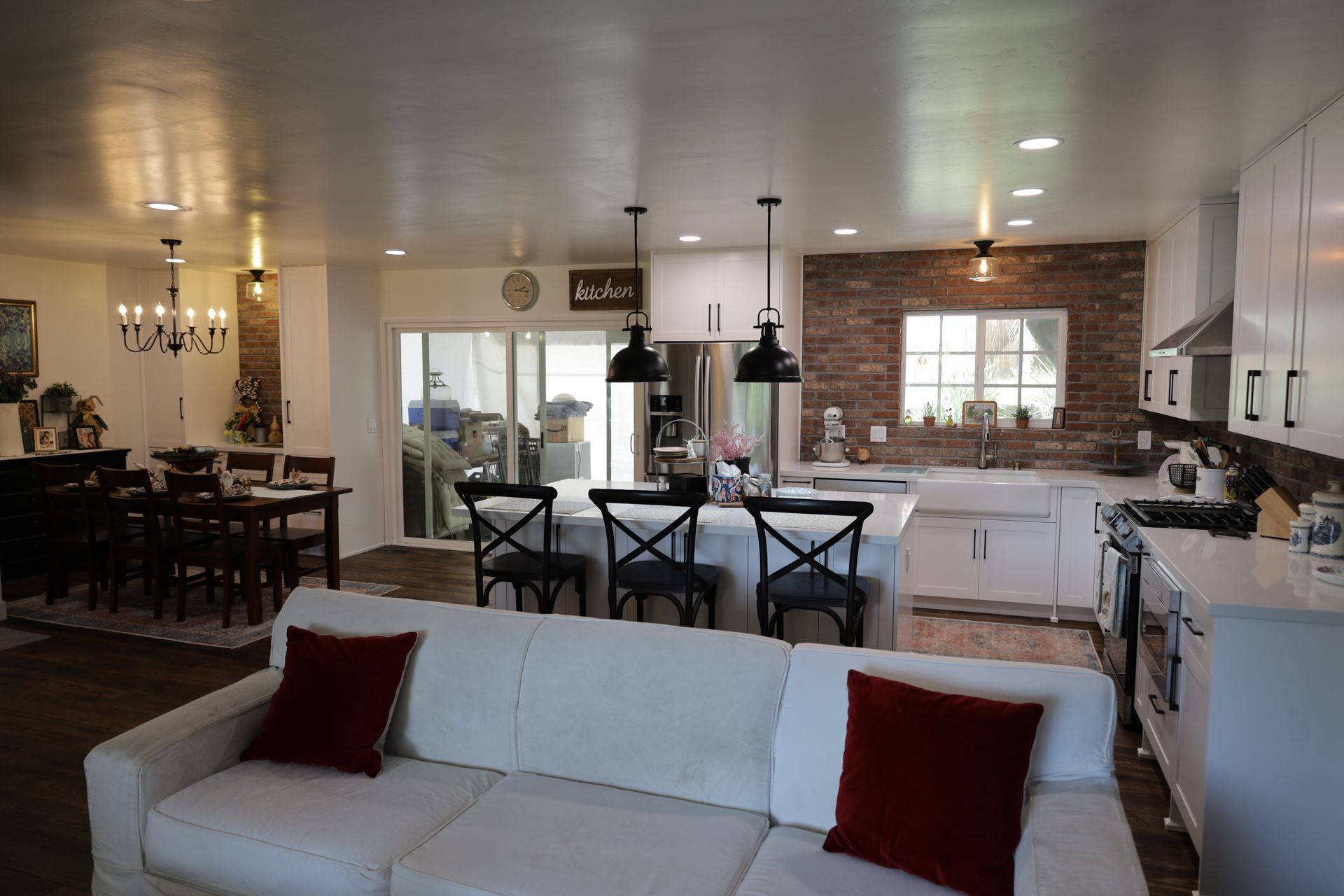 Open-plan kitchen and dining room with white cabinets, dark table, and a sofa in the foreground