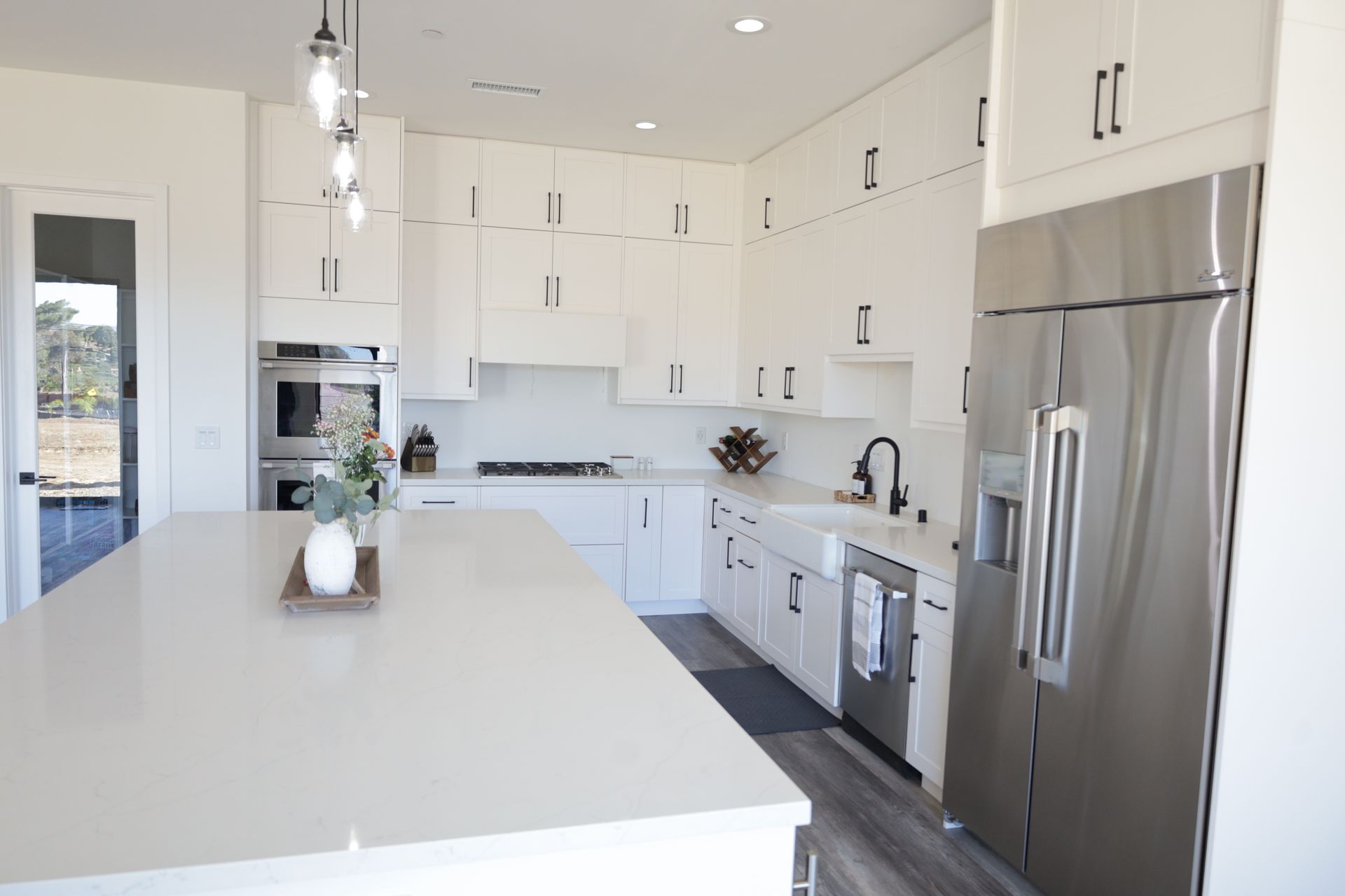 Bright modern white kitchen with stainless steel appliances and a large island counter