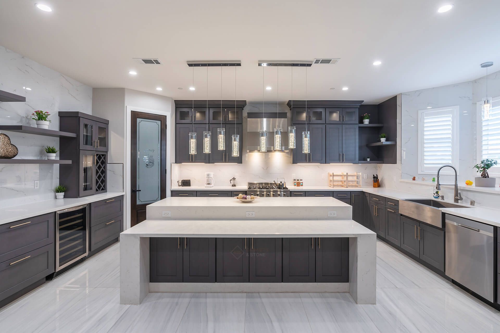 Modern bright kitchen with gray cabinets, white island, stainless appliances, and recessed lighting
