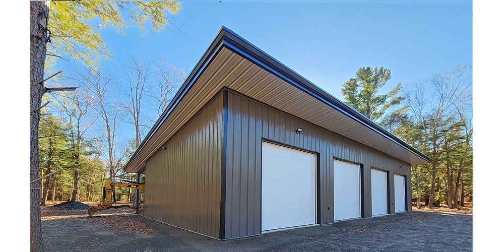 Modern brown metal garage with three white doors in a wooded setting
