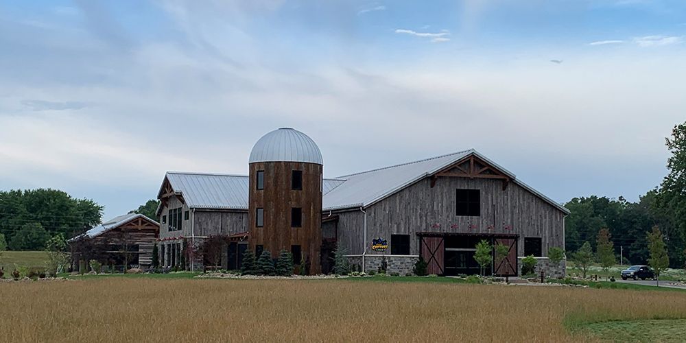 Rustic barn and silo on a grassy field under a cloudy sky