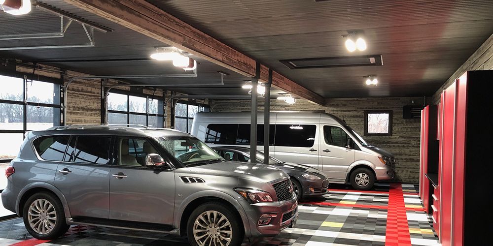Indoor parking garage with several parked SUVs under bright ceiling lights, including gray and white vehicles.