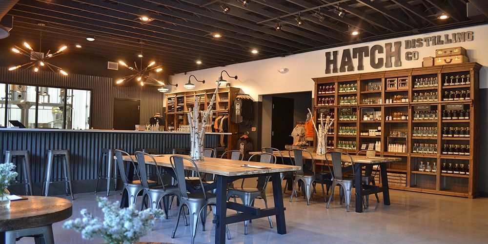 Cozy restaurant interior with hanging lights, wooden tables, and a wall of shelves behind the bar