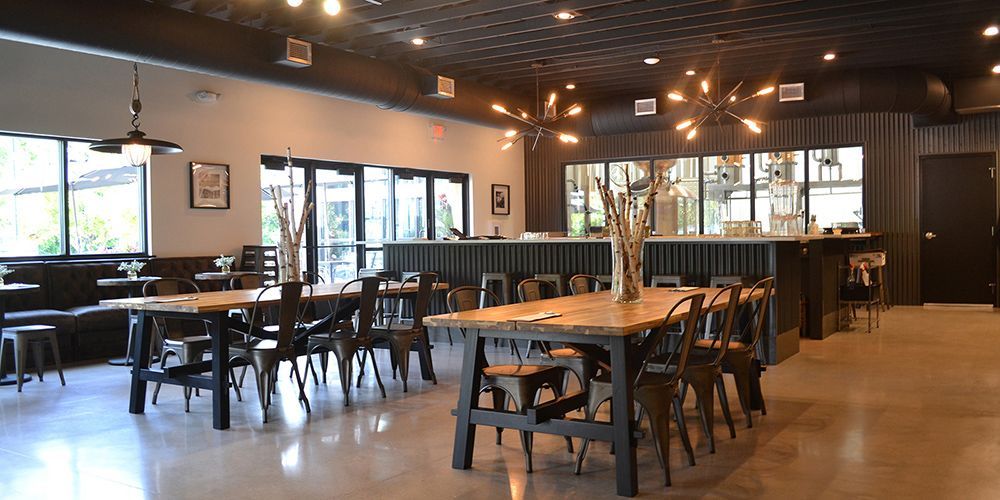 Empty restaurant dining area with wooden tables and chairs under warm lighting